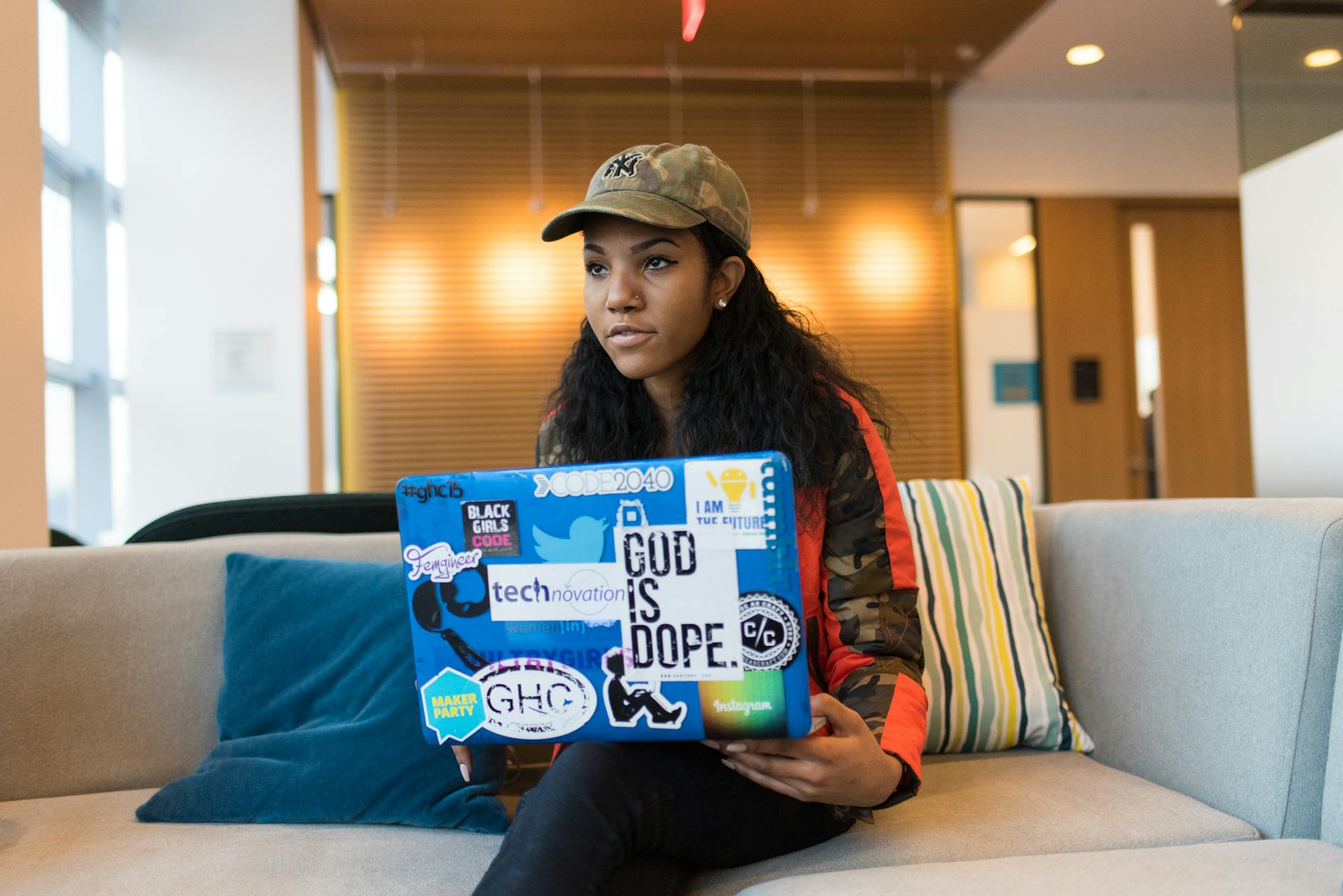 woman holding blue box while sitting on white couch